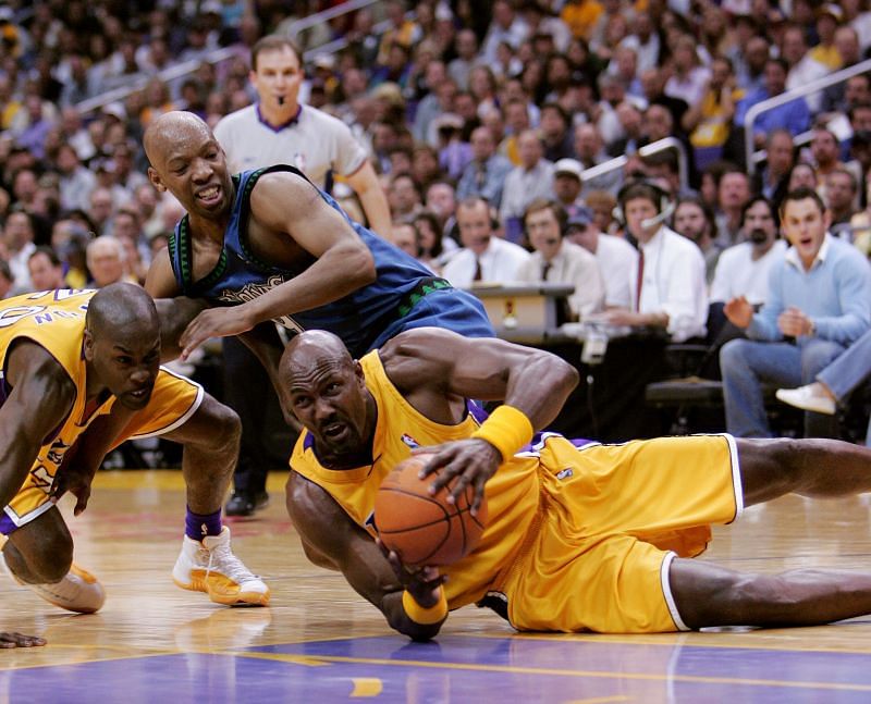 Karl Malone #11 tries to keep control of a loose ball as Gary Payton #20 of the Lakers and Sam Cassell try to fend each other off.