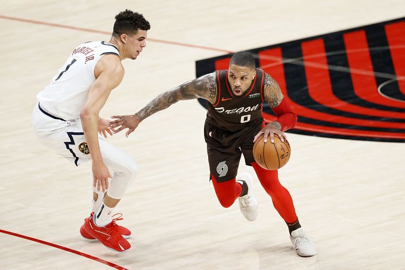 Damian Lillard (#0) dribbles against Michael Porter Jr. (#1).