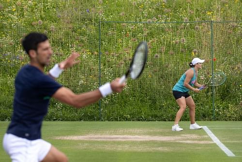 Novak Djokovic training on Tuesday with Ashleigh Barty in the background