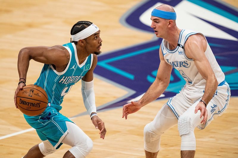 Devonte&#039; Graham #4 of the Charlotte Hornets is guarded by Alex Caruso #4 of the LA Lakers.