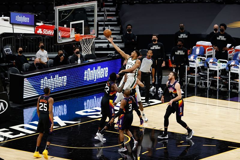 Giannis Antetokounmpo #34 of the Milwaukee Bucks lays up a shot over Deandre Ayton #22 of the Phoenix Suns.