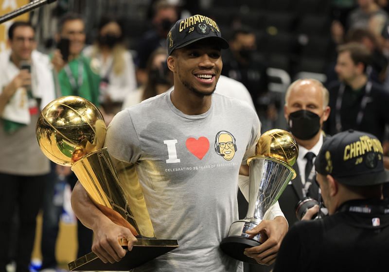 Giannis Antetokounmpo #34 holds the Bill Russell NBA Finals MVP Award and the Larry O&#039;Brien Championship Trophy.