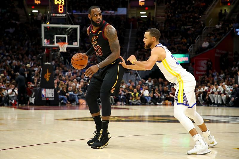 LeBron James #23 drives to the basket defended by Stephen Curry #30.