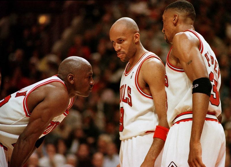 Michael Jordan (left) discusses strategy with teammates Ron Harper (center) and Scottie Pippen (right).