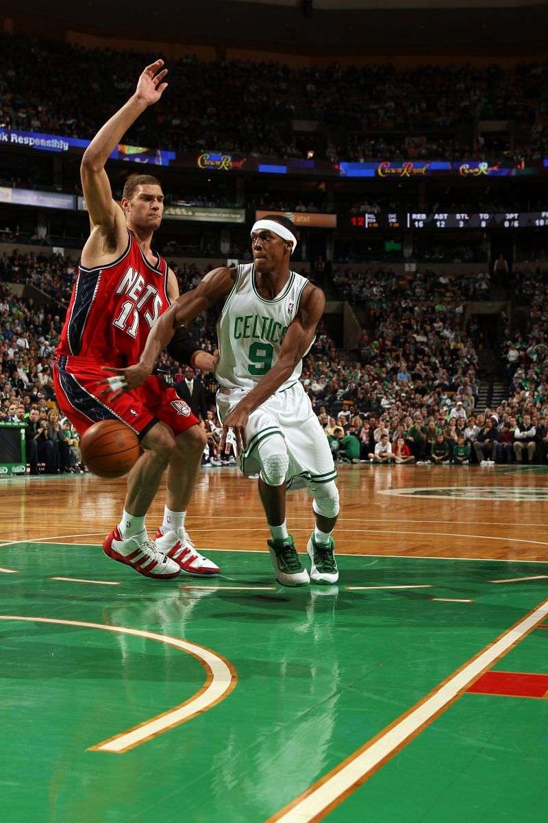 Rajon Rondo #9 of the Boston Celtics makes a pass in the lane against Brook Lopez #11 of the New Jersey Nets