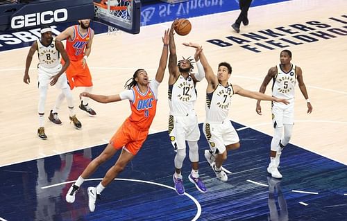 Moses Brown #9 and Oshae Brissett #12 and Malcolm Brogdon #7 reach for a rebound