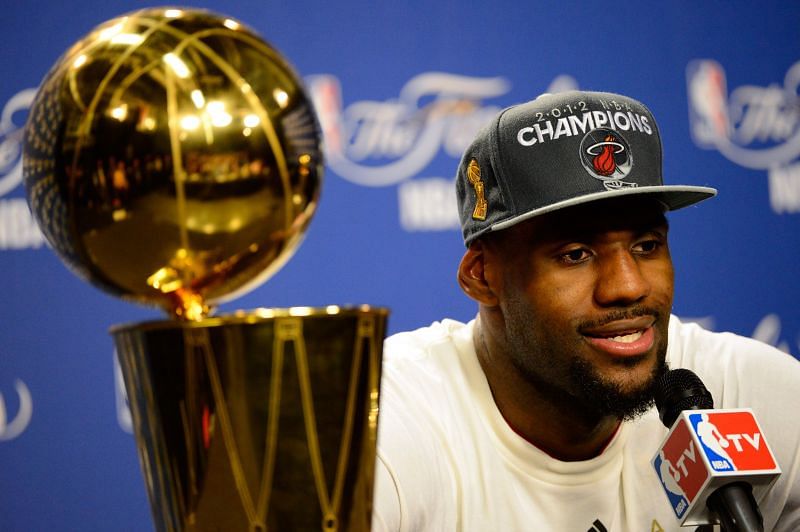 LeBron James #6 of the Miami Heat answers questions from the media next to the Larry O'Brien Finals Championship trophy.