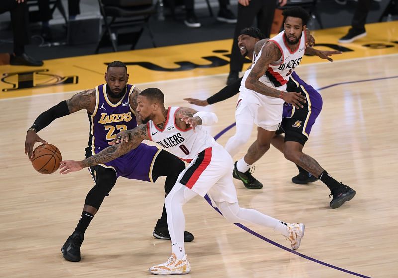Damian Lillard of the Portland Trail Blazers reaches for the ball against LeBron James of the LA Lakers.
