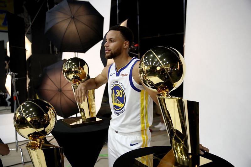 Stephen Curry poses with his three Larry O&#039;Brien NBA championship trophies.