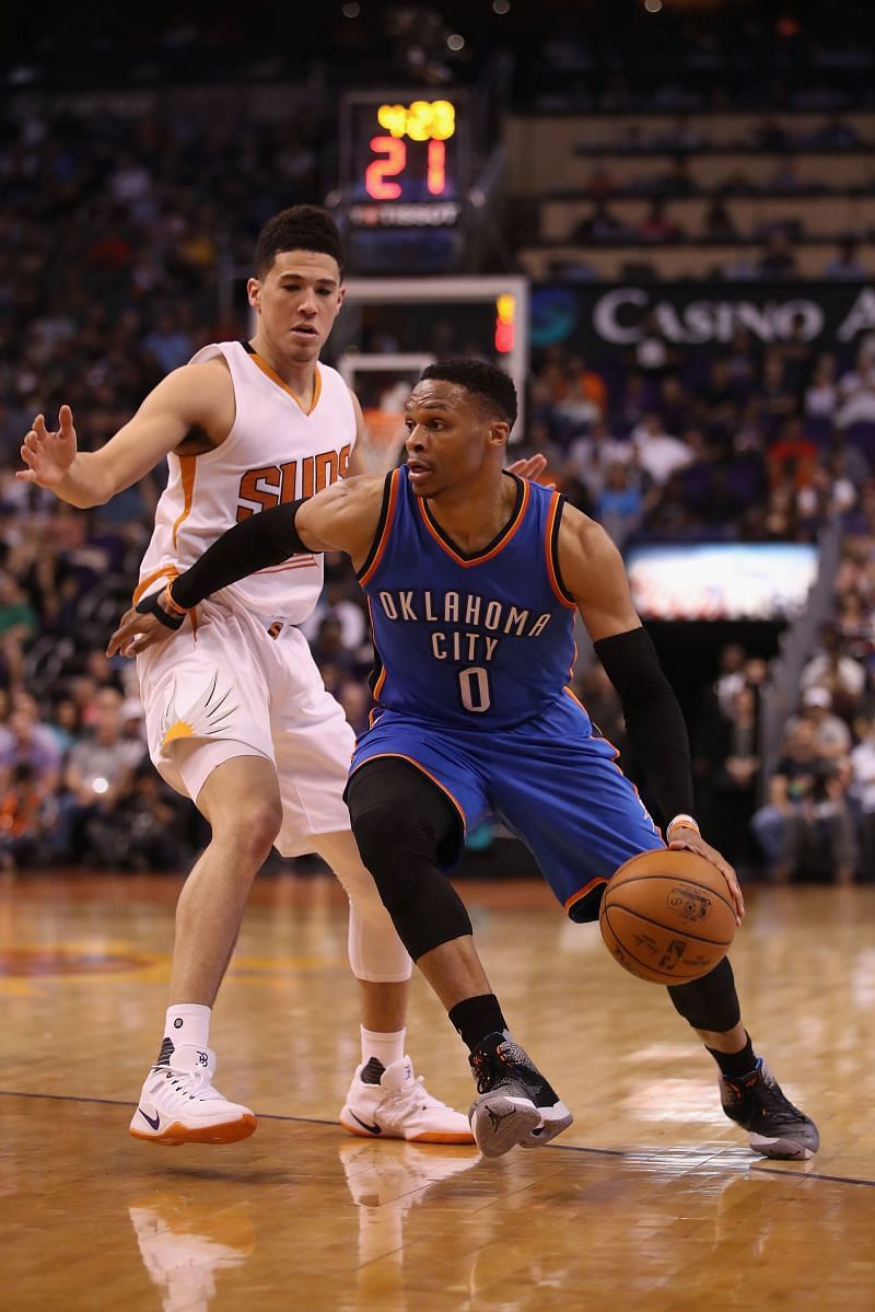 Russell Westbrook #0 of the Oklahoma City Thunder moves the ball past Devin Booker #1 of the Phoenix Suns