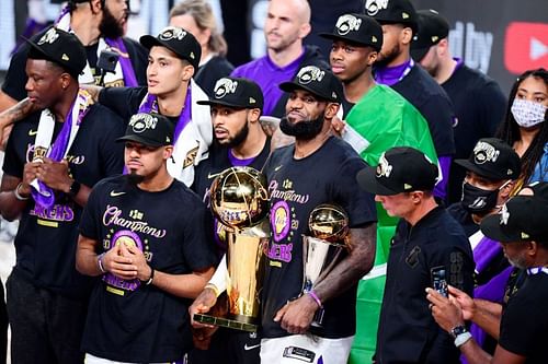 LeBron James #23 holds the Finals MVP trophy and with the NBA championship trophy.