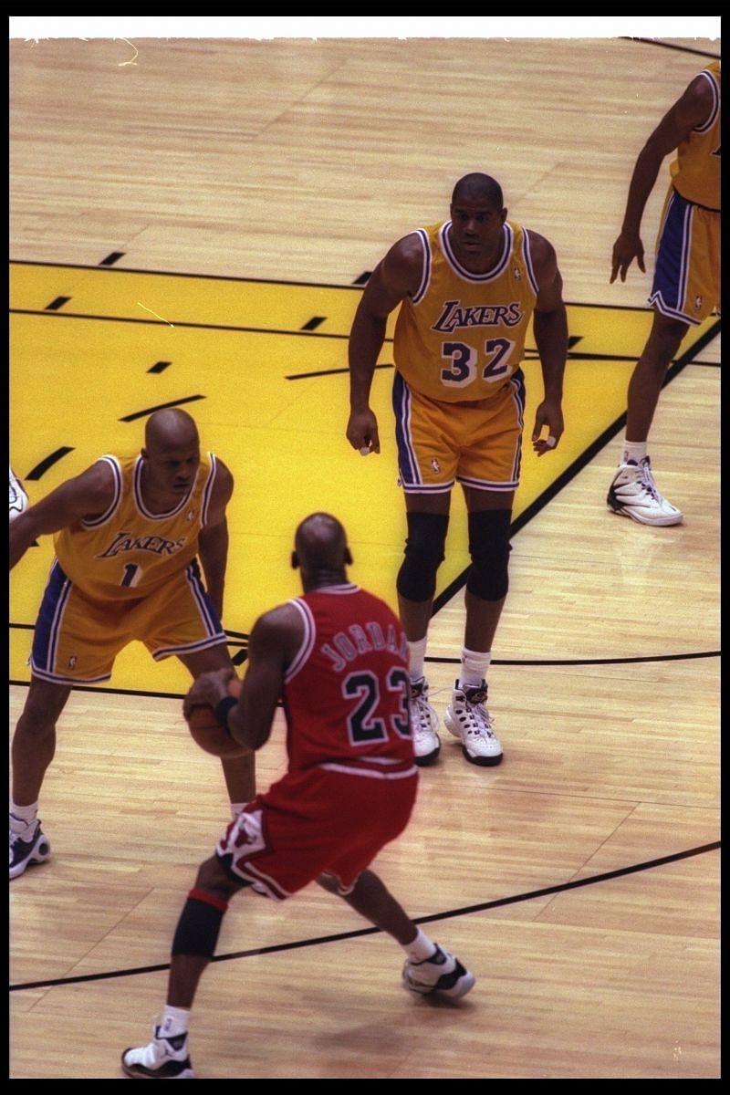 Guard Earvin (Magic) Johnson of the LA Lakers looks on as Chicago Bulls guard Michael Jordan moves the ball.