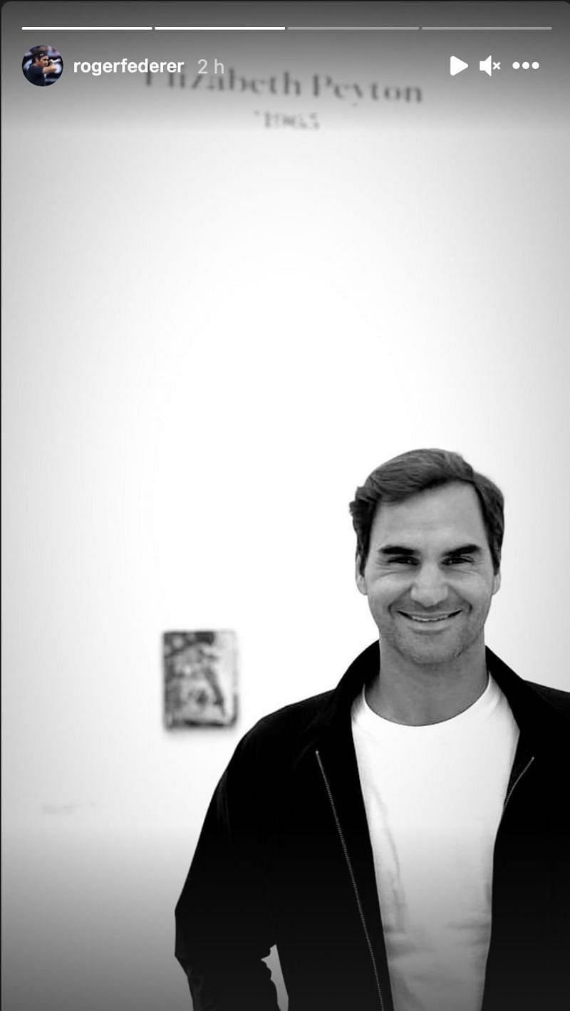 Roger Federer poses in front of an art piece.