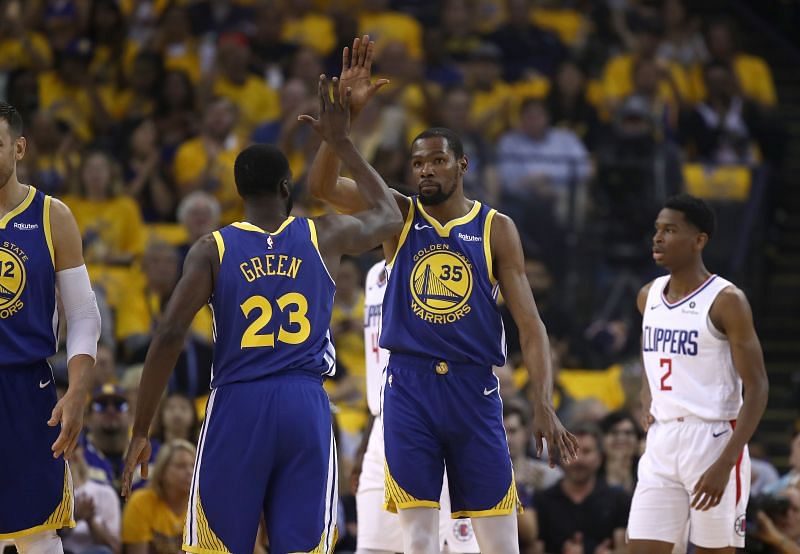 Kevin Durant #35 high-fives Draymond Green #23 on the court during a game