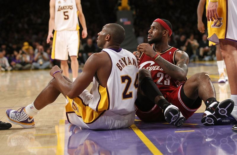 Kobe Bryant #24 and LeBron James #23 sit on the floor after falling during play.