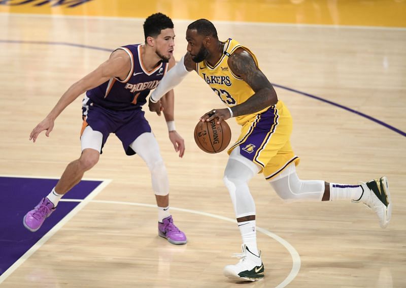 LeBron James #23 of the Los Angeles Lakers drives on Devin Booker #1 of the Phoenix Suns