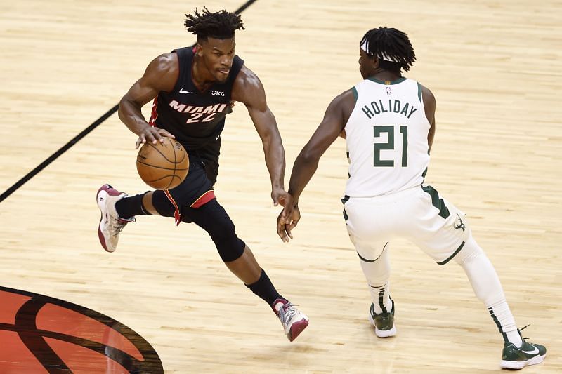 Jimmy Butler (#22) of the Miami Heat dribbles up the court, defended by Jrue Holiday (#21) of the Milwaukee Bucks.