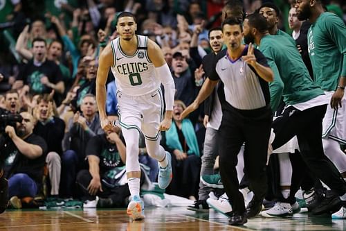 Jason Tatum celebrates with the Boston Celtics' bench after scoring a basket.