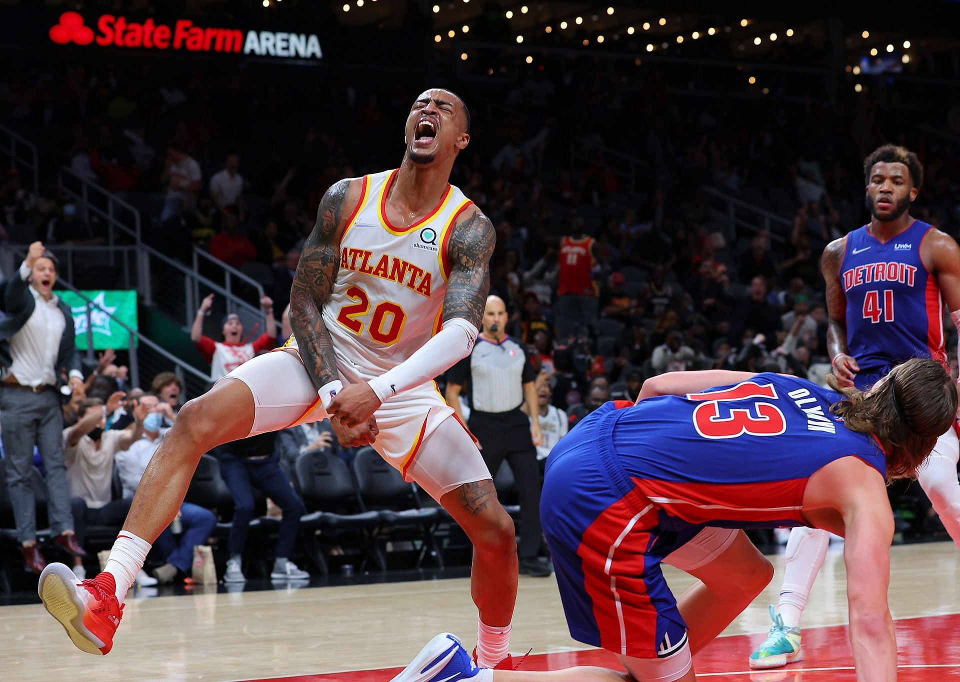 John Collins of the Atlanta Hawks reacts after dunking over Kelly Olynyk of the Detroit Pistons.