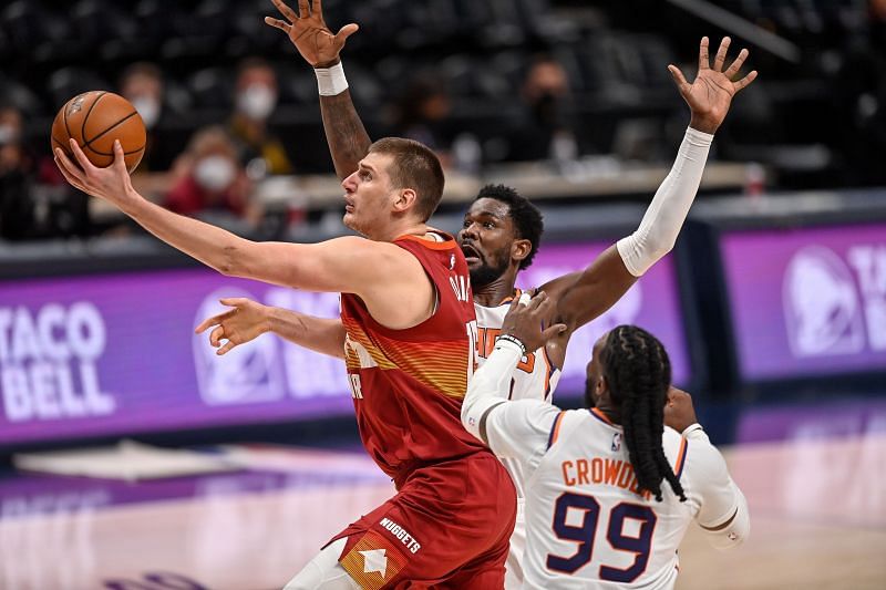 Nikola Jokic #15 of the Denver Nuggets scores on a layup after driving past Jae Crowder #99 and Deandre Ayton #22 of the Phoenix Suns in Game Four of the Western Conference second-round playoff series at Ball Arena on June 13, 2021 in Denver, Colorado.
