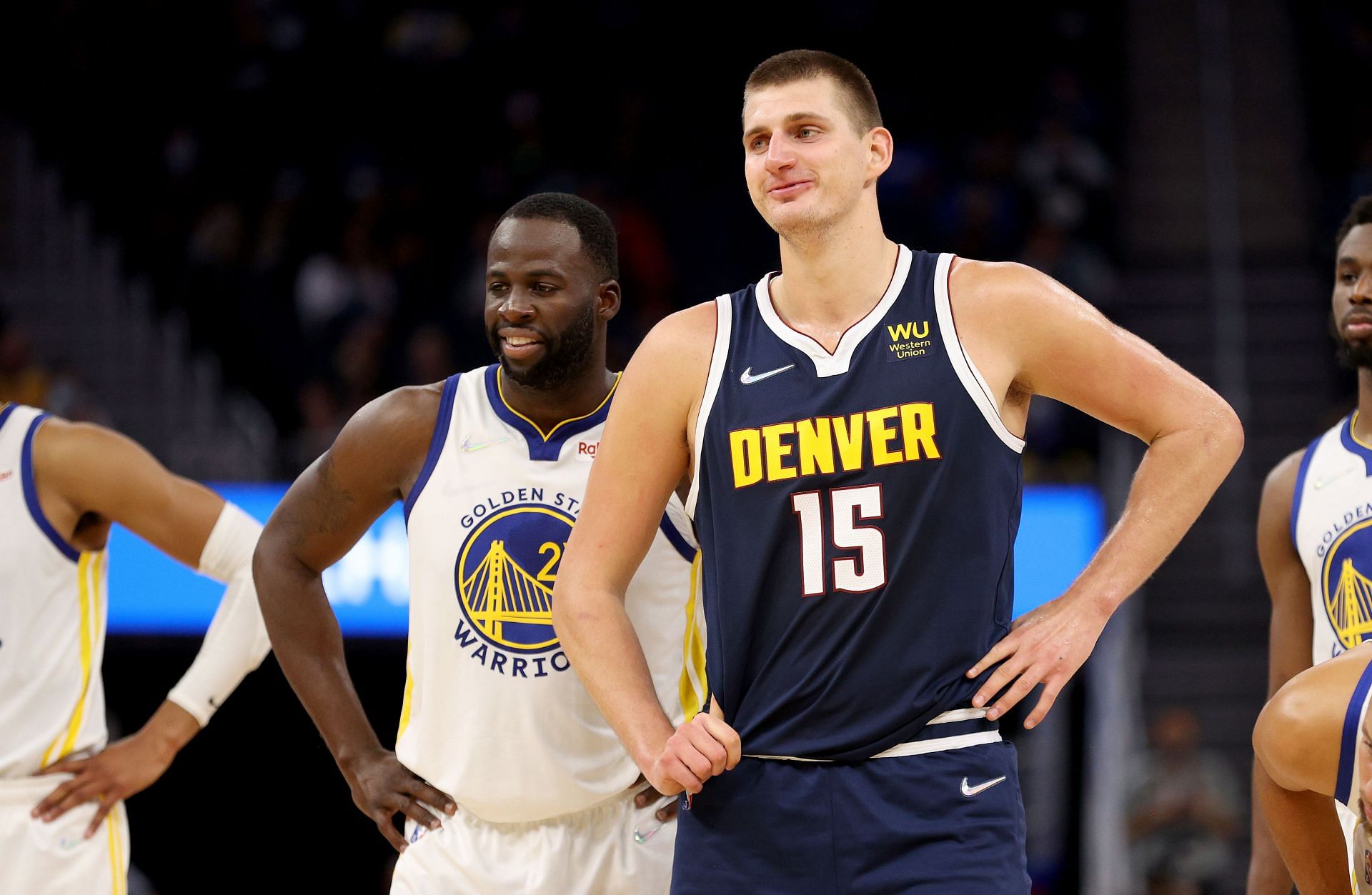 Nikola Jokic stands next to Draymond Green