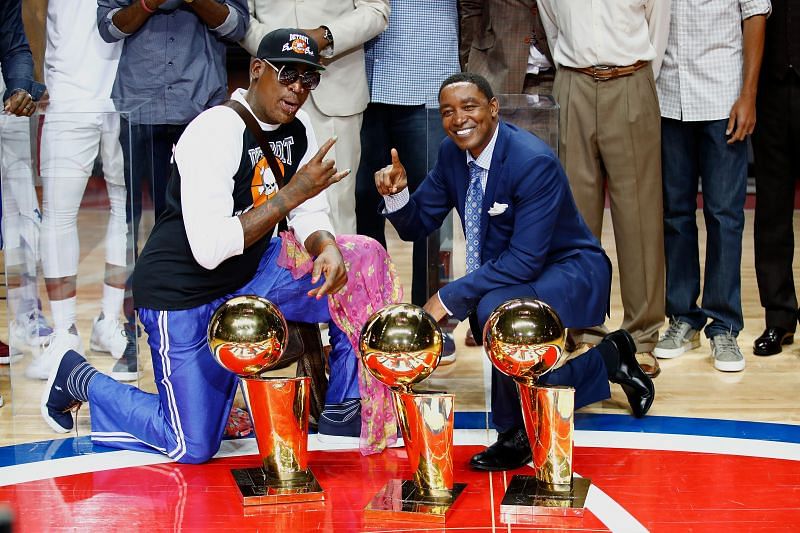 Former Detroit Pistons Dennis Rodman and Isiah Thomas pose with three Larry O&#039;Brien championship trophies.