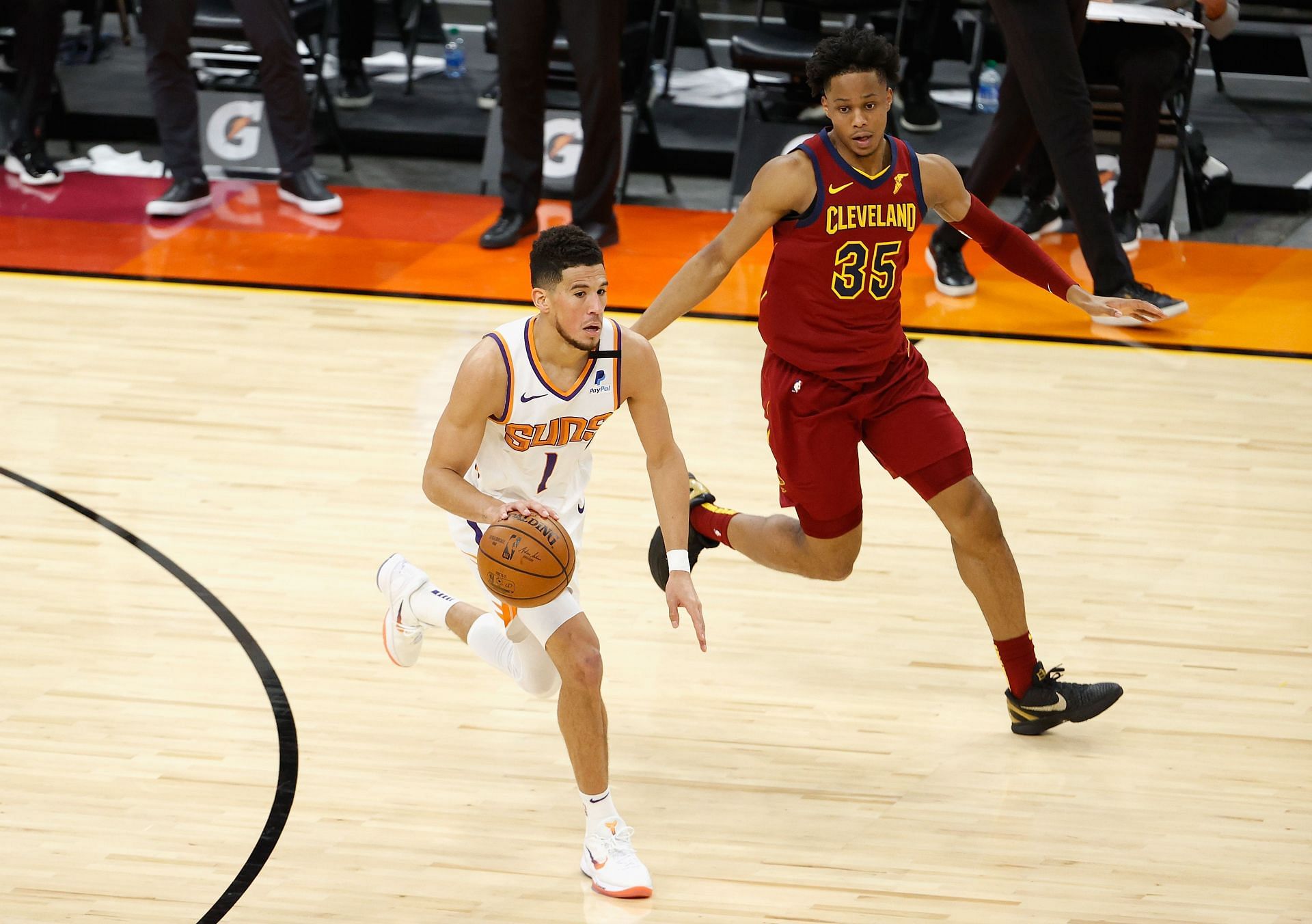 Devin Booker of the Phoenix Suns dribbles past Isaac Okoro of the Cleveland Cavaliers.