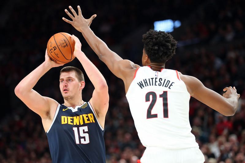 Nikola Jokic #15 of the Denver Nuggets looks to pass the ball against Hassan Whiteside #21 of the Portland Trail Blazers in the fourth quarter during their season opener at Moda Center on October 23, 2019 in Portland, Oregon.
