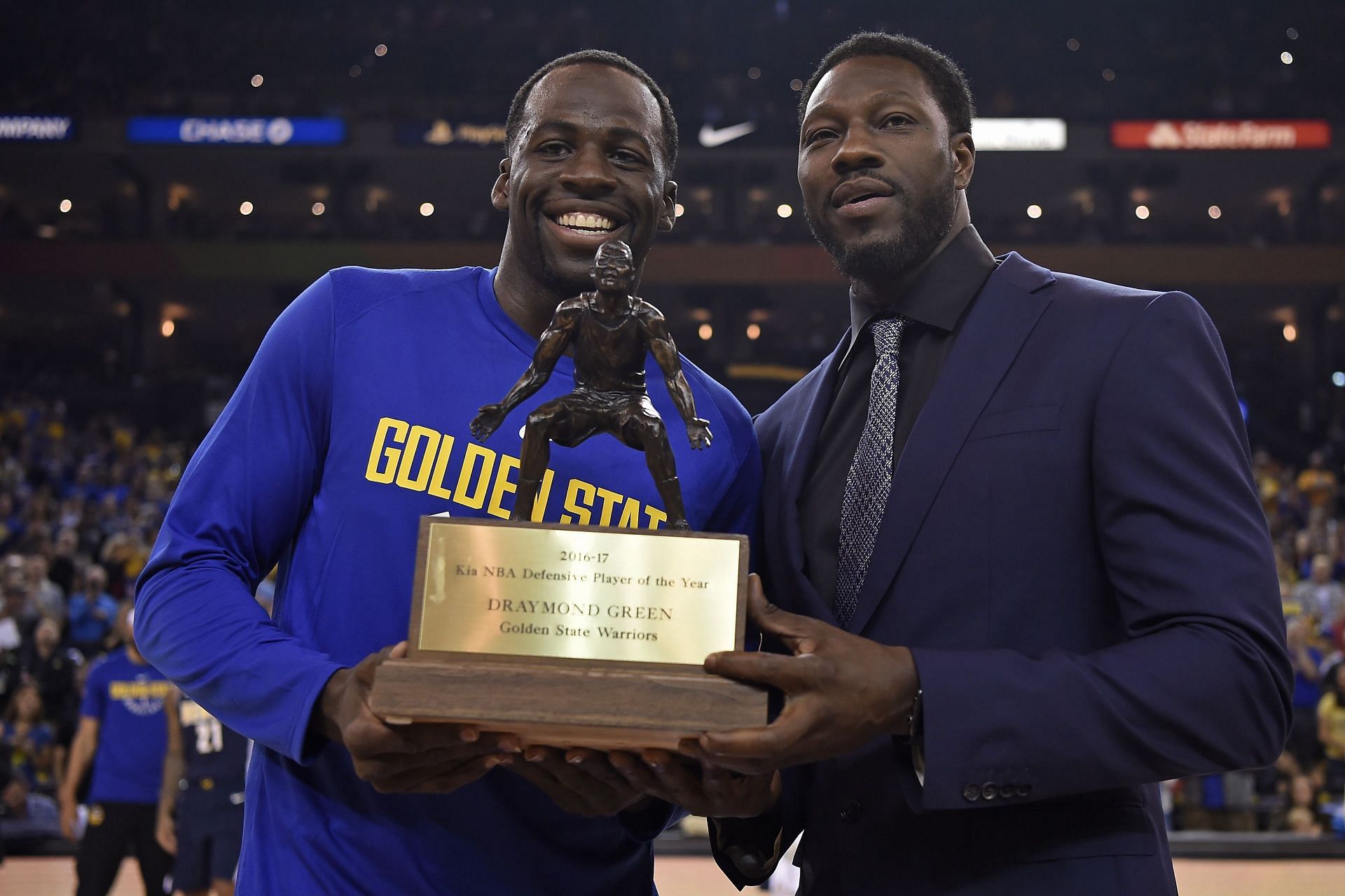 Draymond Green is handed the NBA DPOY trophy by Ben Wallace. Photo Credit: Bay Area News Group/Jose Carlos Fajardo.