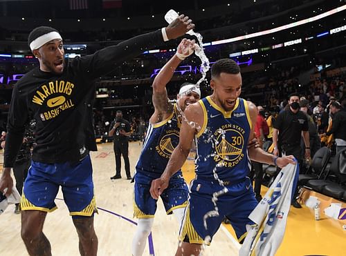 Gary Payton II and Damion Lee of the Golden State Warriors shower Stephen Curry with water.