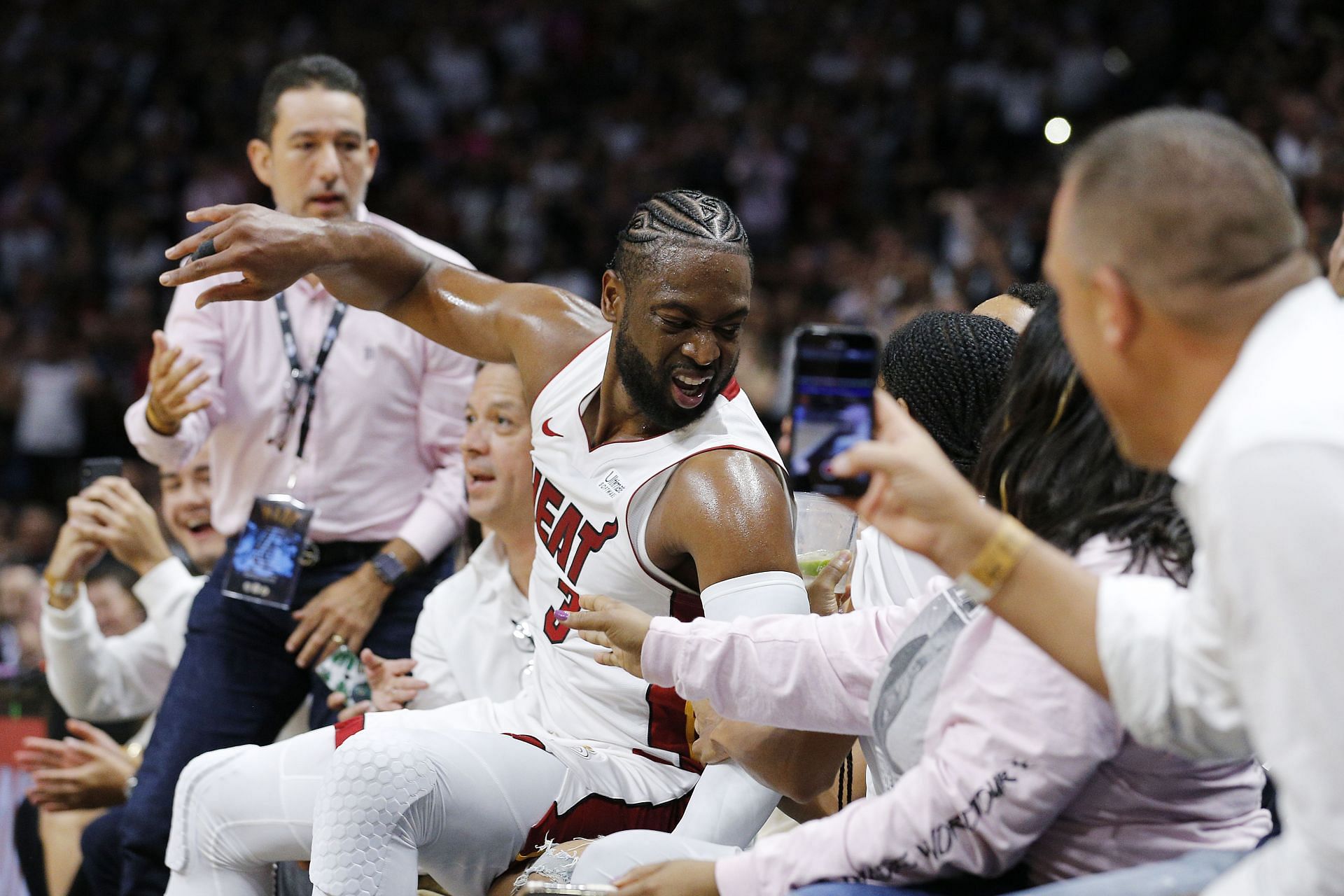 Dwyane Wade #3 of the Miami Heat falls into the fans after shooting a three pointer against the Philadelphia 76ers during the second half at American Airlines Arena on April 09, 2019 in Miami, Florida.