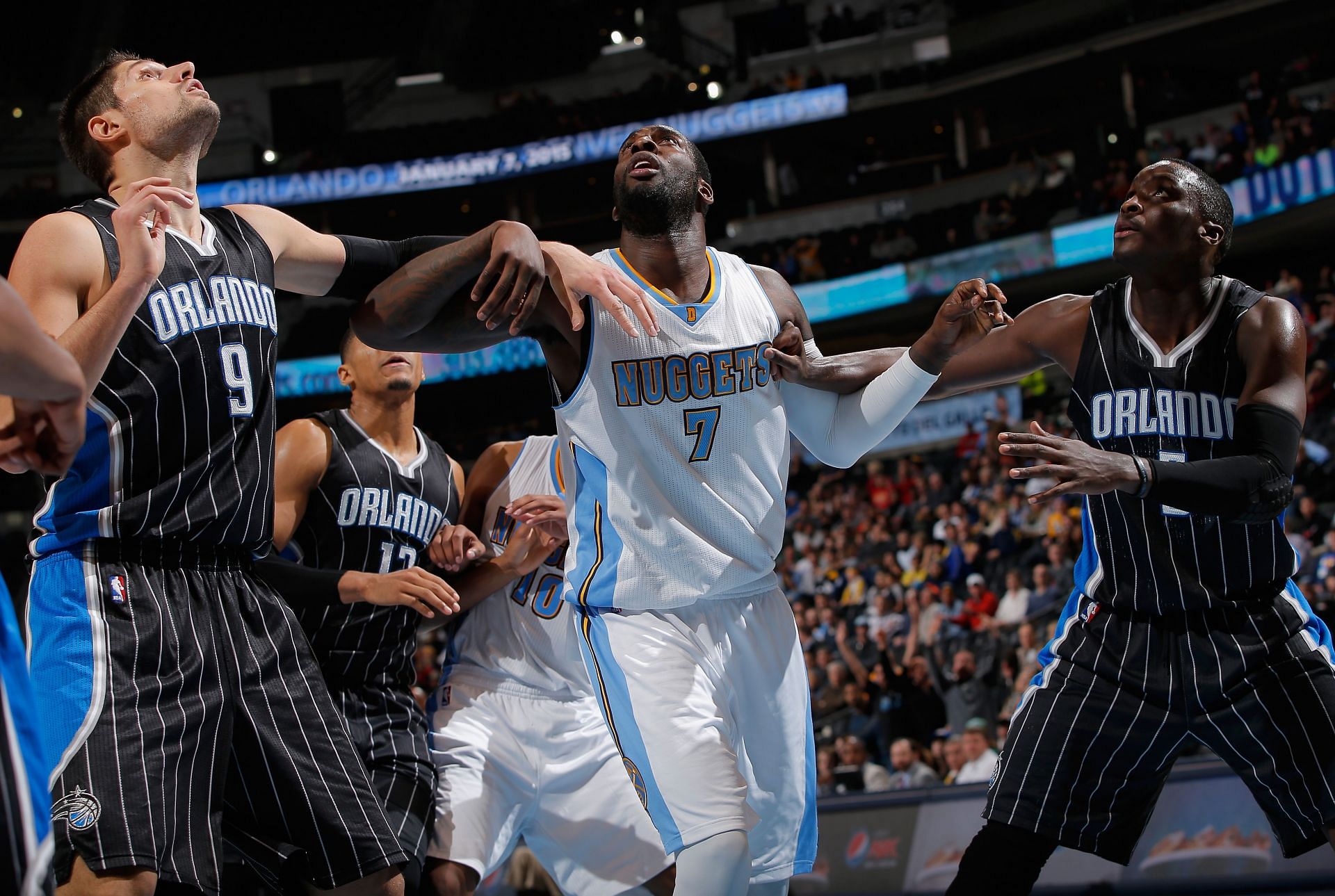 J.J. Hickson #7 of the Denver Nuggets battles for rebounding position against Nikola Vucevic #9 and Victor Oladipo #5 of the Orlando Magic at Pepsi Center on January 7, 2015 in Denver, Colorado. The Nuggets defeated the Magic 93-90.