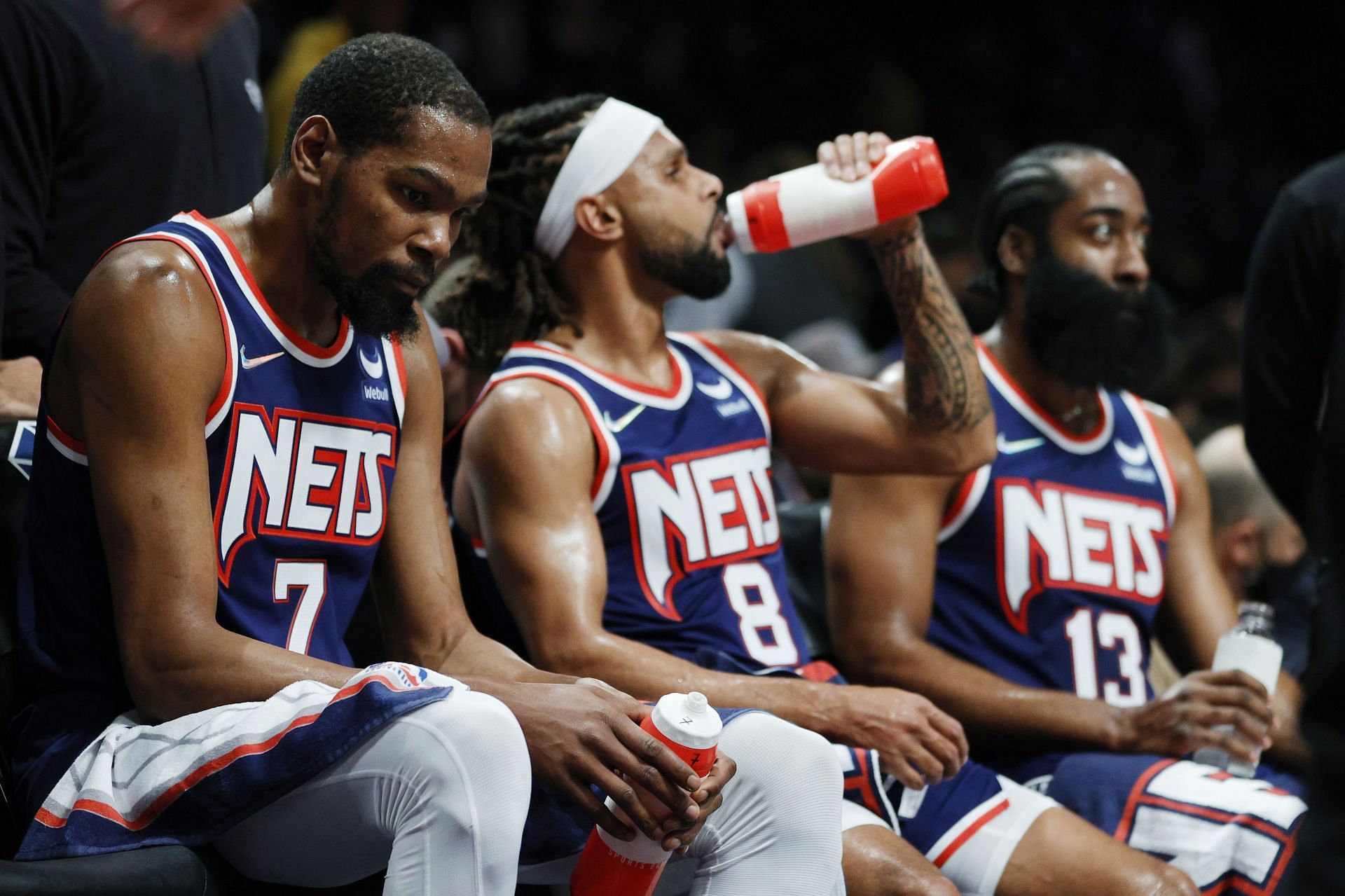 Kevin Durant (7), Patty Mills (8) and James Harden (13) of the Brooklyn Nets look on from the bench