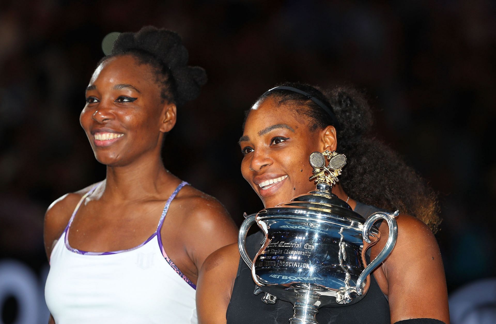 Venus (L) and Serena Williams pose with the trophy ahead of the 2017 Australian Open