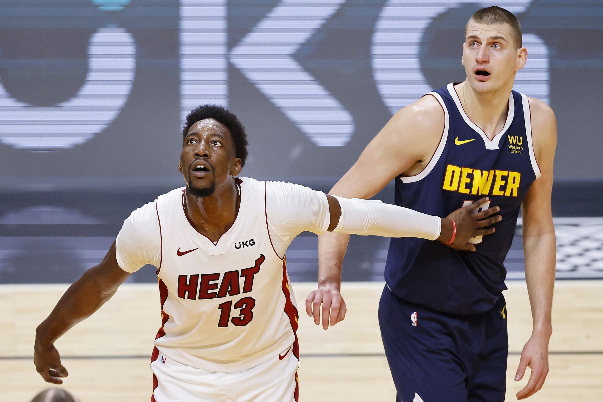 Bam Adebayo #13 of the Miami Heat and Nikola Jokic #15 of the Denver Nuggets look on during the first quarter at American Airlines Arena on January 27, 2021 in Miami, Florida.
