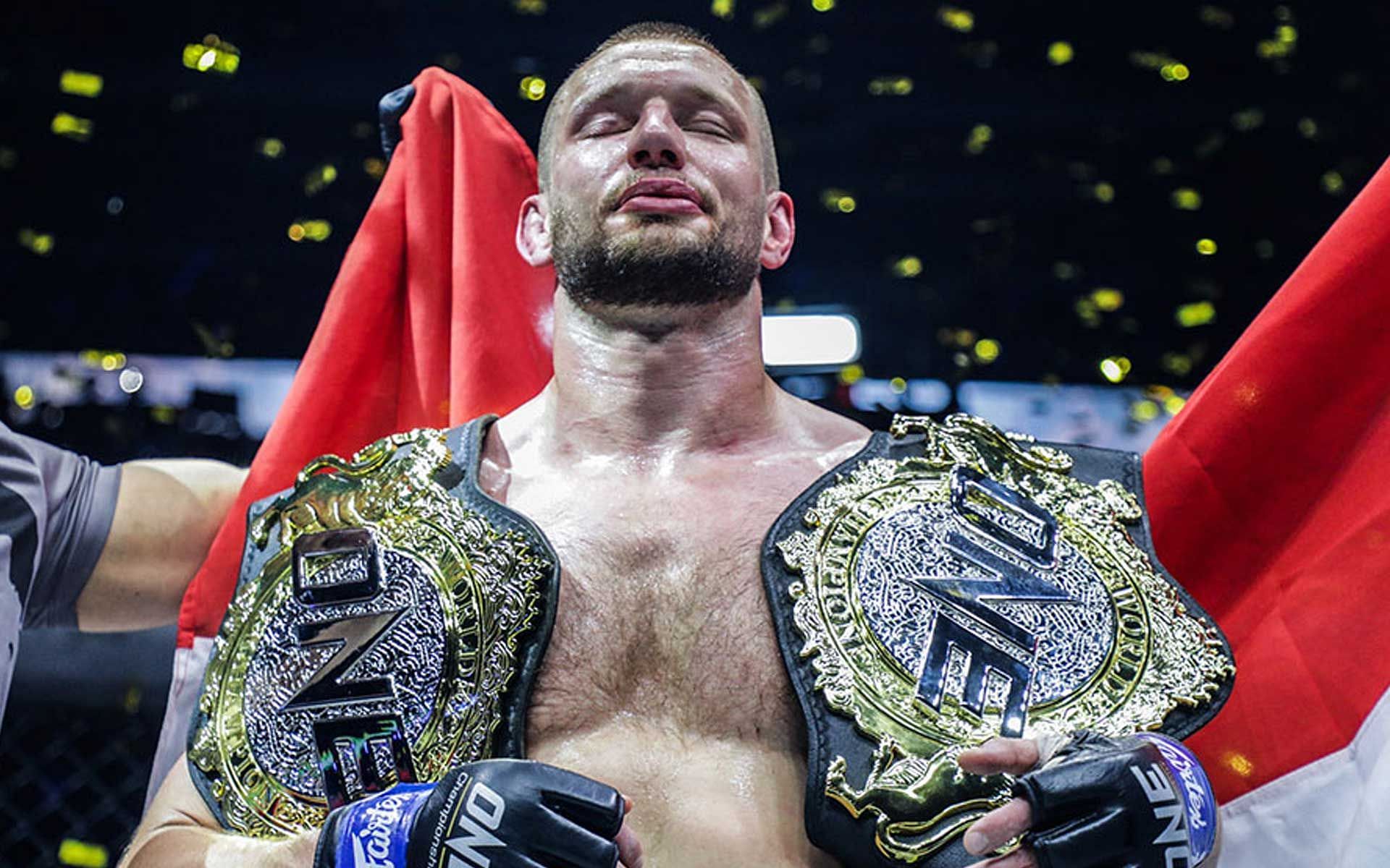 ONE middleweight and light heavyweight world champion Reinier de Ridder holds both belts over his shoulders [Photo courtesy of ONE Championship]