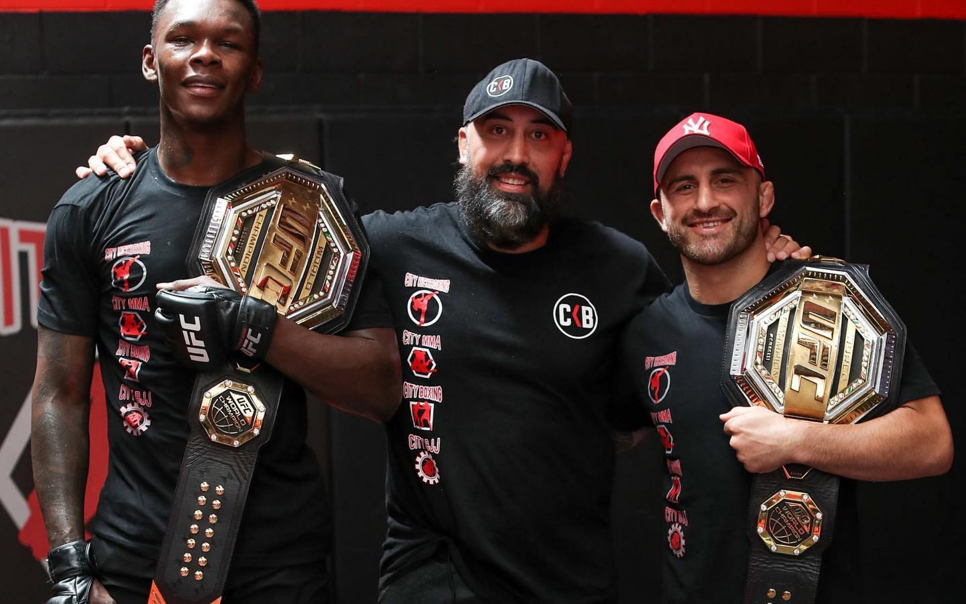 Eugene Bareman (center) with Israel Adesanya (left) and Alexander Volkanovski (right) [Credits: @city_kickboxing via Instagram]