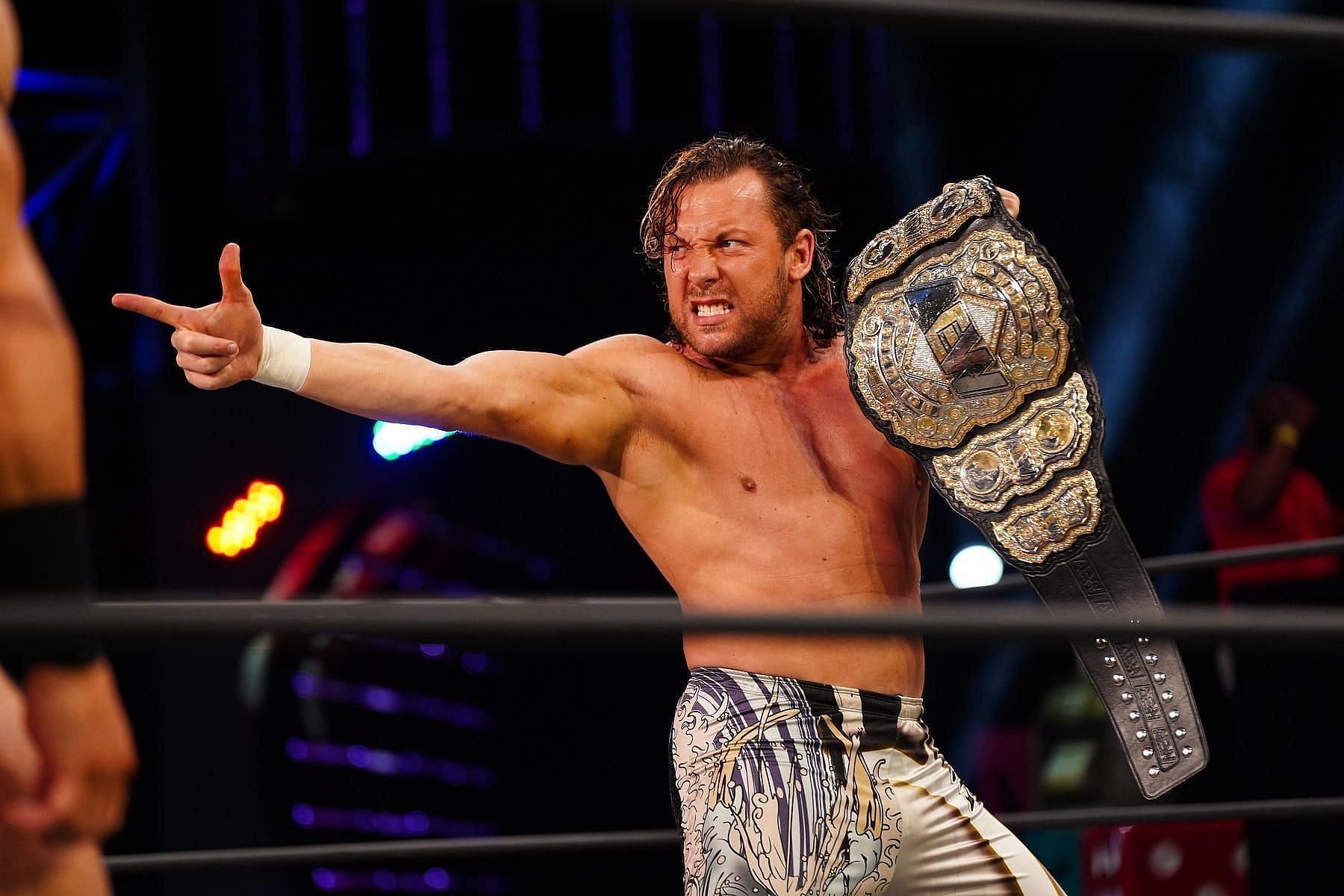 Kenny Omega posing with the world title at an AEW show.