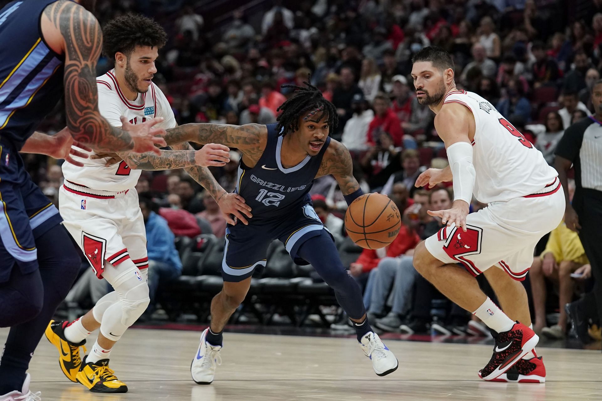 Ja Morant #12 of the Memphis Grizzlies dribbles the ball past Lonzo Ball #2 and Nikola Vucevic #9 of the Chicago Bulls in the second half during a preseason game at United Center on October 15, 2021 in Chicago, Illinois.