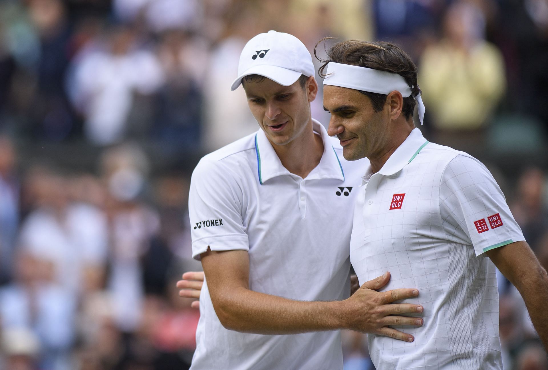 Hubert Hurkacz and Roger Federer sharing an exchange at the net following their encounter at Wimbledon