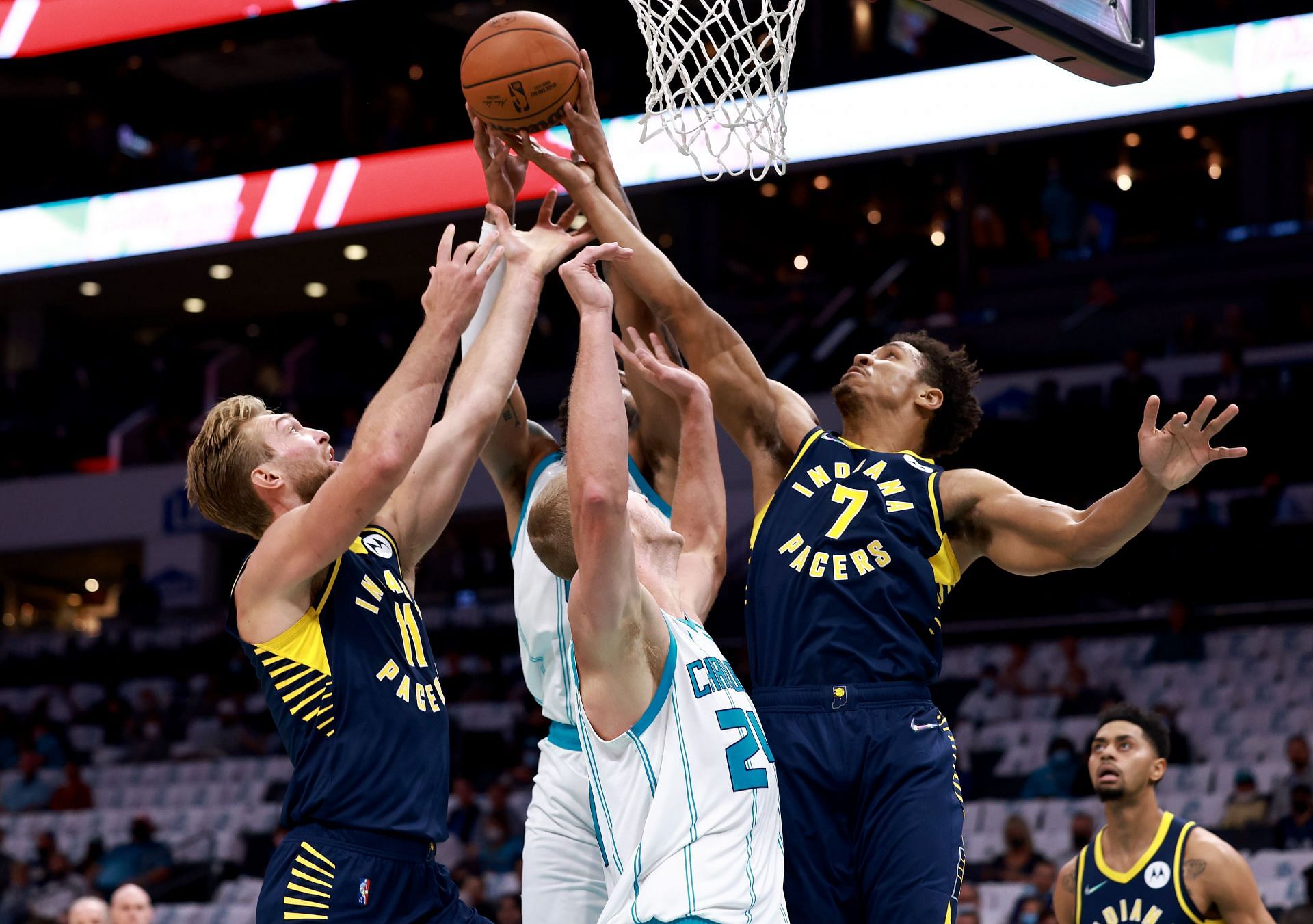 Domantas Sabonis #11 and Malcolm Brogdon #7 of the Indiana Pacers battle Mason Plumlee #24 and Miles Bridges #0 of the Charlotte Hornets for a rebound during the first half of their game at Spectrum Center on October 20, 2021 in Charlotte, North Carolina.