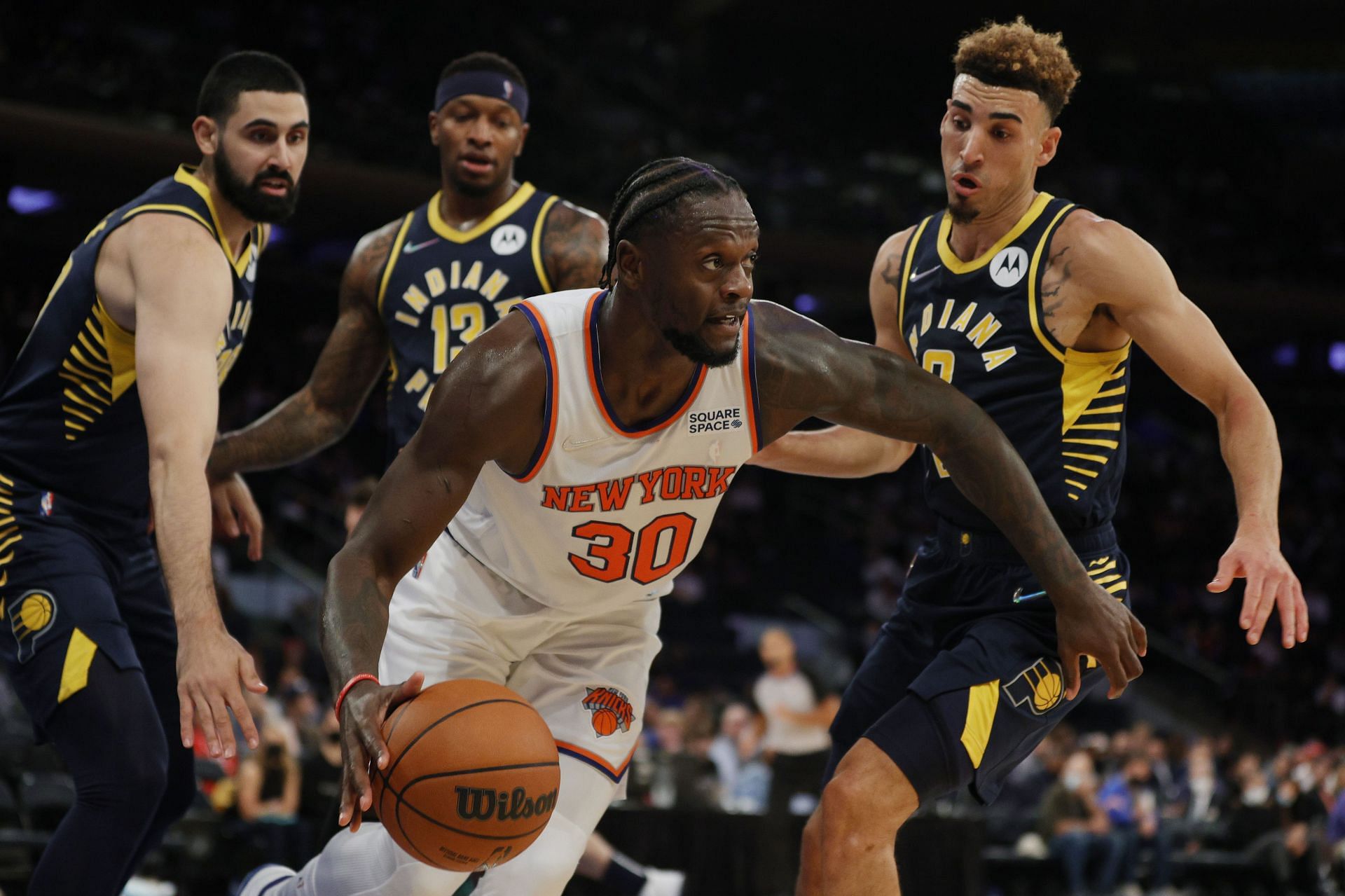 Julius Randle #30 of the New York Knicks dribbles the ball as Goga Bitadze #88, Chris Duarte #3, and Torrey Craig #13 of the Indiana Pacers defend during the second half of a preseason game at Madison Square Garden on October 05, 2021 in New York City. The Knicks won 125-104.