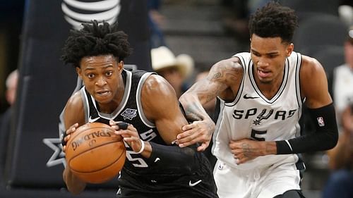 DeAaron Fox of the Sacramento Kings drives past Dejounte Murray of the San Antonio Spurs.