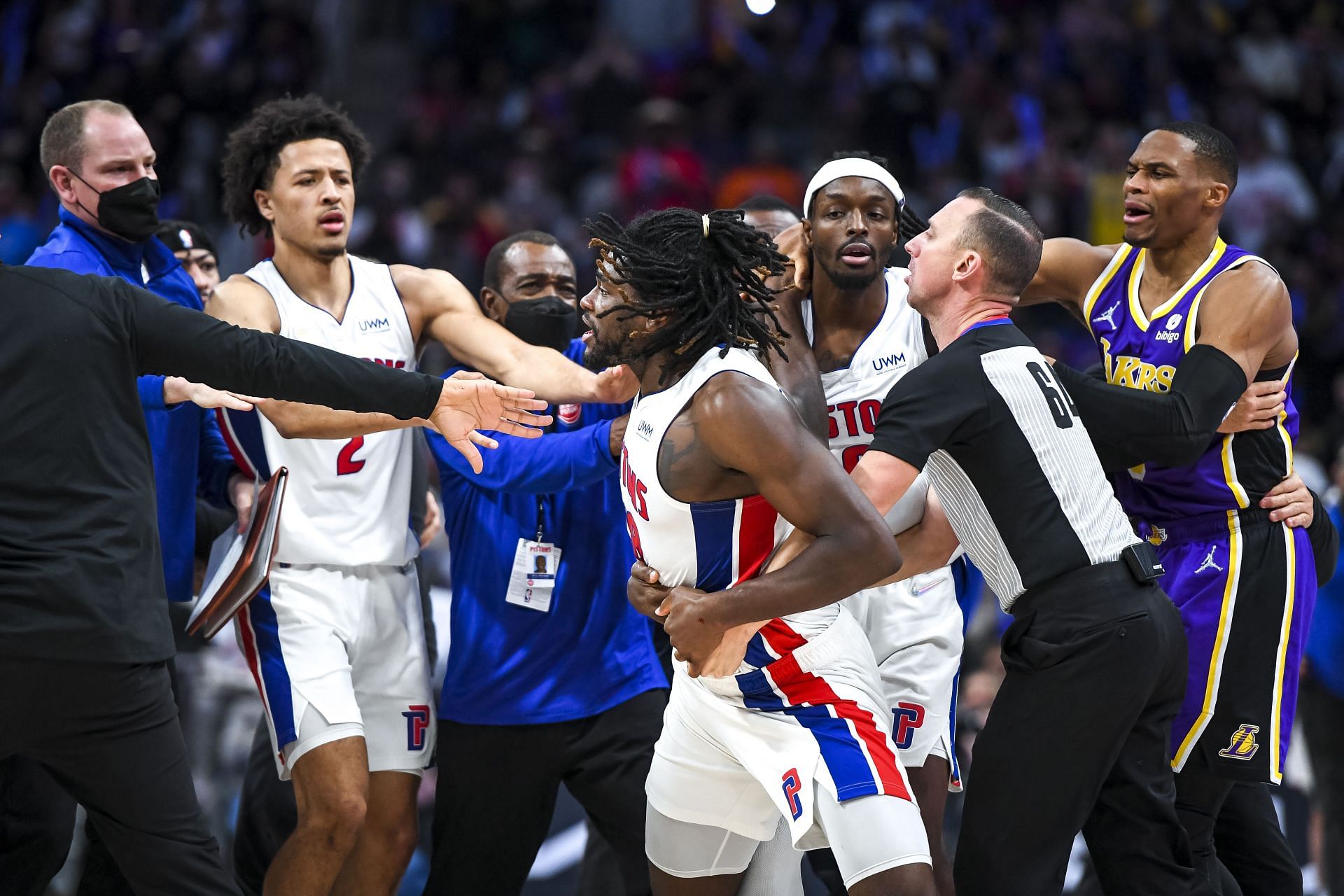 The referee and Detroit Pistons players trying to calm down a heated Isaiah Stewart
