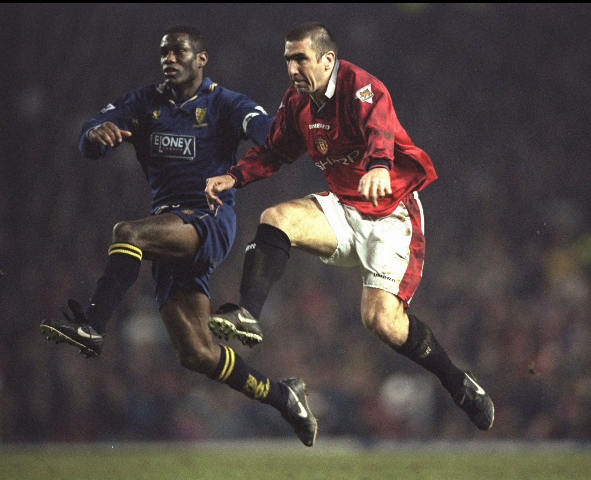 Eric Cantona of Manchester United (right) goes for the ball With Robbie Earle of Wimbledon