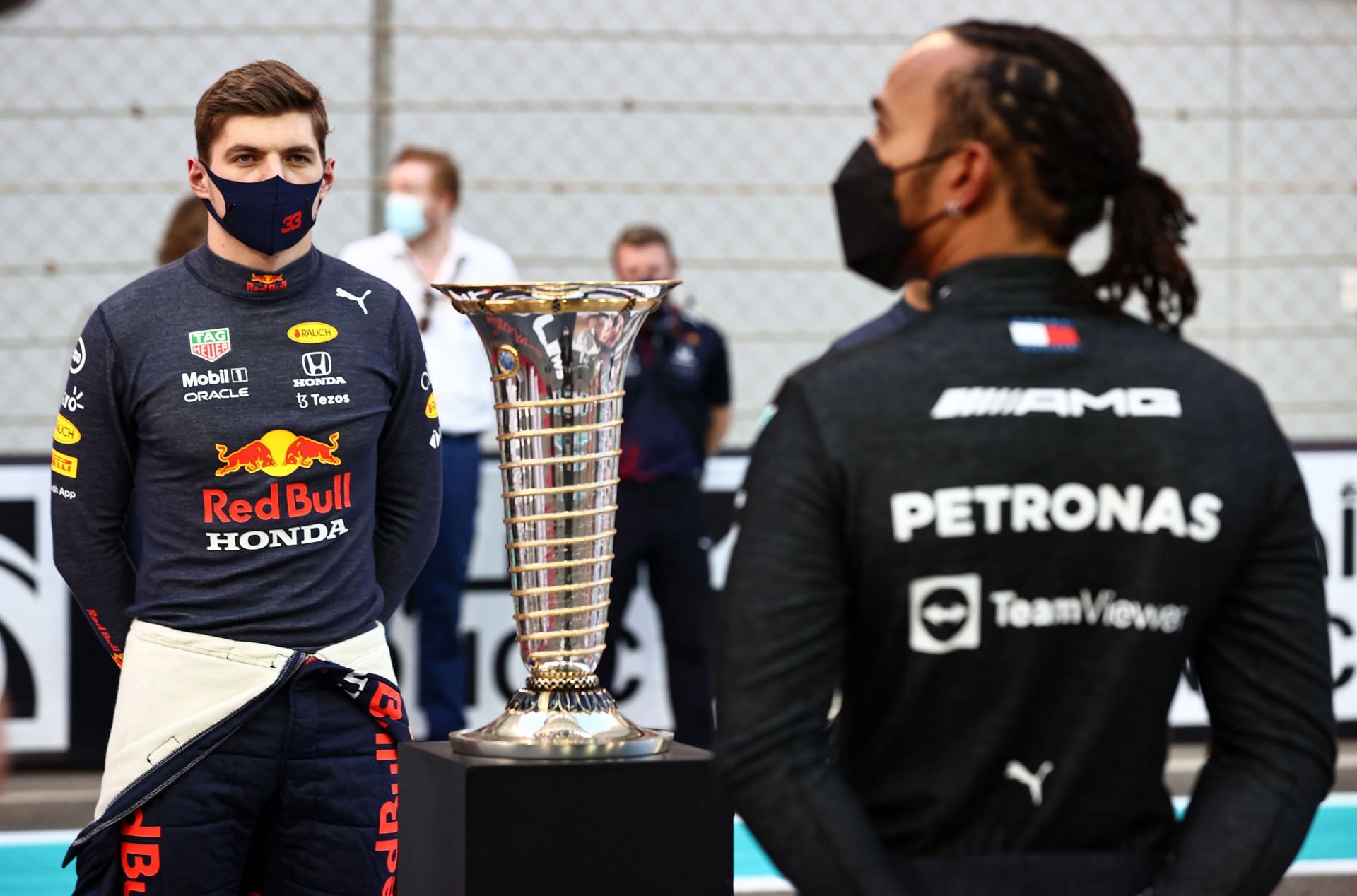 2021 championship contenders Max Verstappen and Lewis Hamilton stand in front of the F1 World Drivers Championship Trophy on the grid before the Abu Dhabi GP (Photo by Mark Thompson/Getty Images)