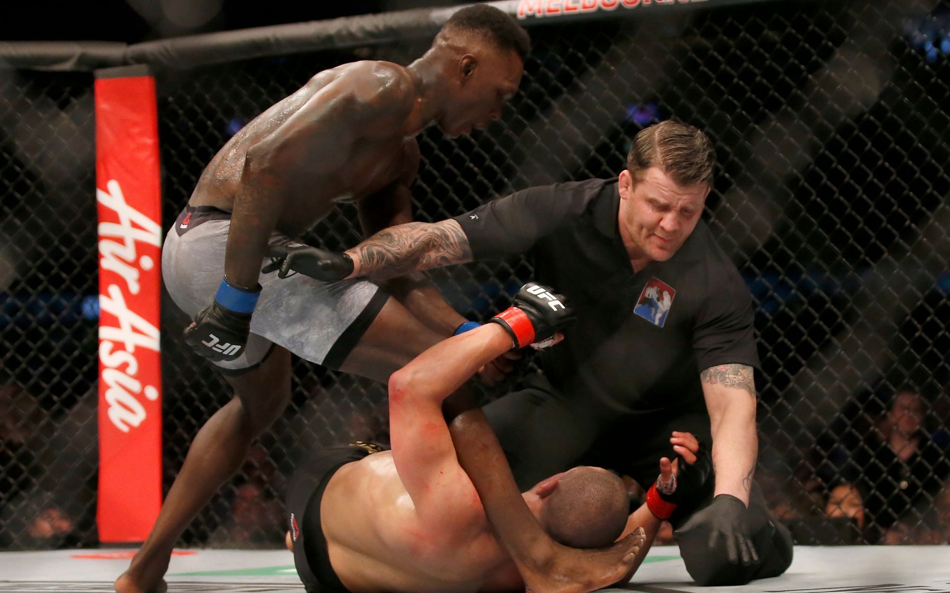 The referee stops the UFC 243 main event between Israel Adesanya (standing) and Robert Whittaker (on the ground) in Melbourne