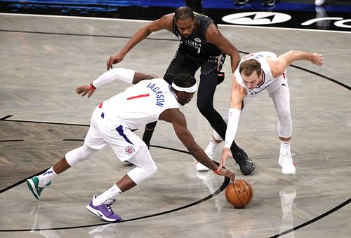 Reggie Jackson and Luke Kennard of the LA Clippers steal the loose ball from Brooklyn Nets' Kevin Durant