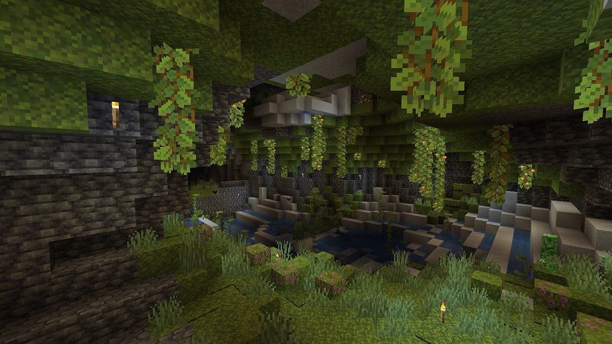 A lush cave lit with torches, strikingly visibly different from a dripstone cave due to its large amount of flora (Image via Mojang)