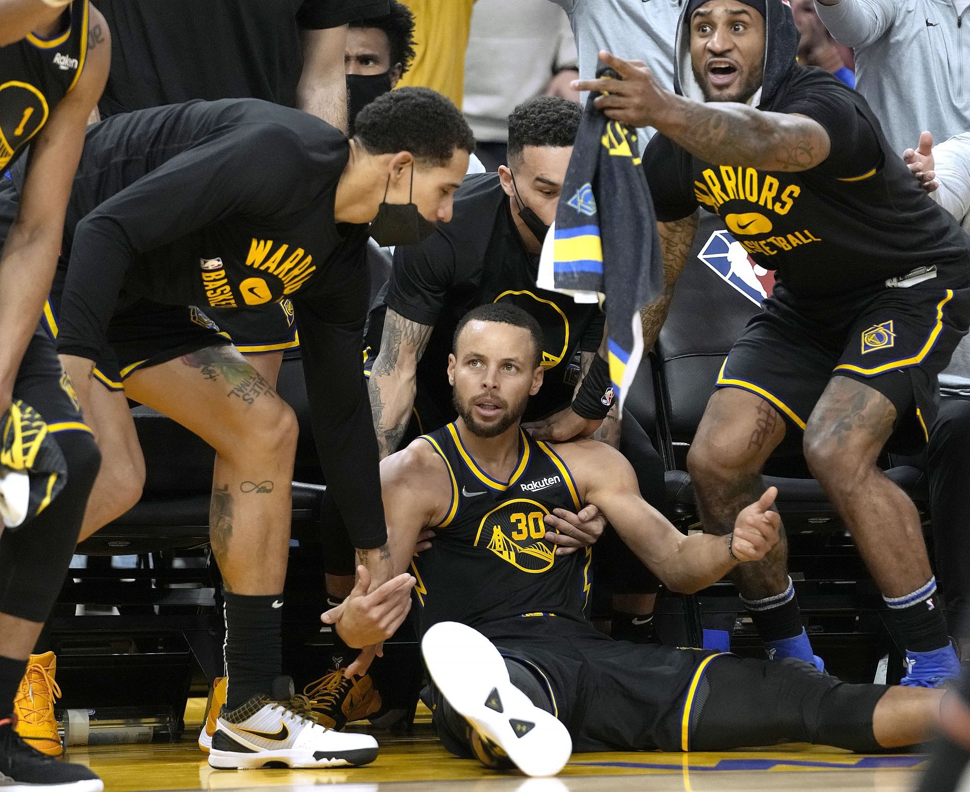 Stephen Curry #30 of the Golden State Warriors falls down in front of his bench after making a three-point shot against the Portland Trail Blazers during the second quarter at Chase Center on December 08, 2021 in San Francisco, California.
